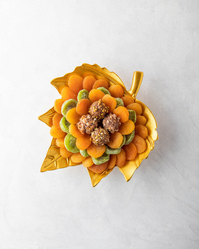 The Golden leaf by NJDNuts, Dates & Dried FruitsYOUR GIFT CONTAINS Content: Dried Kiwis 150gms Dried Apricot 500gms Assorted Truffles - 4pcs Flavors: Assorted truffles with Praline, Ganache and caramel fillings Tray dimensions: Wide: 25cm Height: 26.5cm H