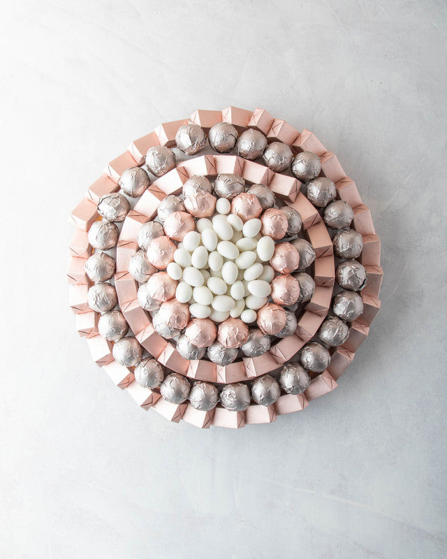 Rose Gold Arrangement by NJDChocolate & ConfectioneryYOUR GIFT CONTAINS Content: Assorted Milk Belgian chocolates 104pcs White Drageè 150gms Flavors: Assorted Chocolates and truffles filled with praline, ganache, Biscoff, roasted nuts and wafer fillings T