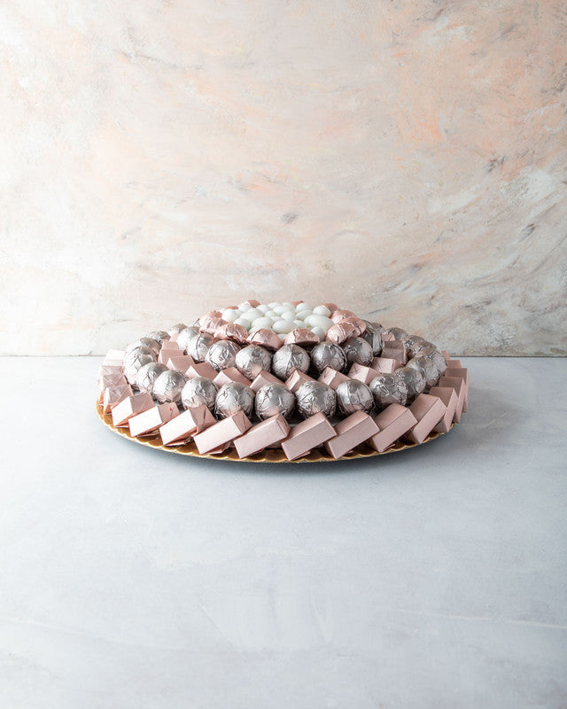 Rose Gold Arrangement by NJDChocolate & ConfectioneryYOUR GIFT CONTAINS Content: Assorted Milk Belgian chocolates 104pcs White Drageè 150gms Flavors: Assorted Chocolates and truffles filled with praline, ganache, Biscoff, roasted nuts and wafer fillings T
