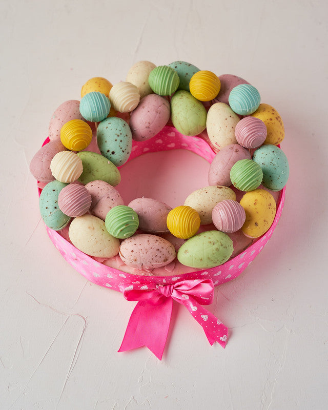 Easter WreathChocolate & ConfectioneryYour Gift Contains: • 12 pieces Belgian chocolate truffles • Flavors: Kinder, Roche, Pistachio and Lotus • 22 pieces assorted color chocolate Easter Eggs • Wreath Size: 23x23x4cm Handling and Storage • Keep away from
