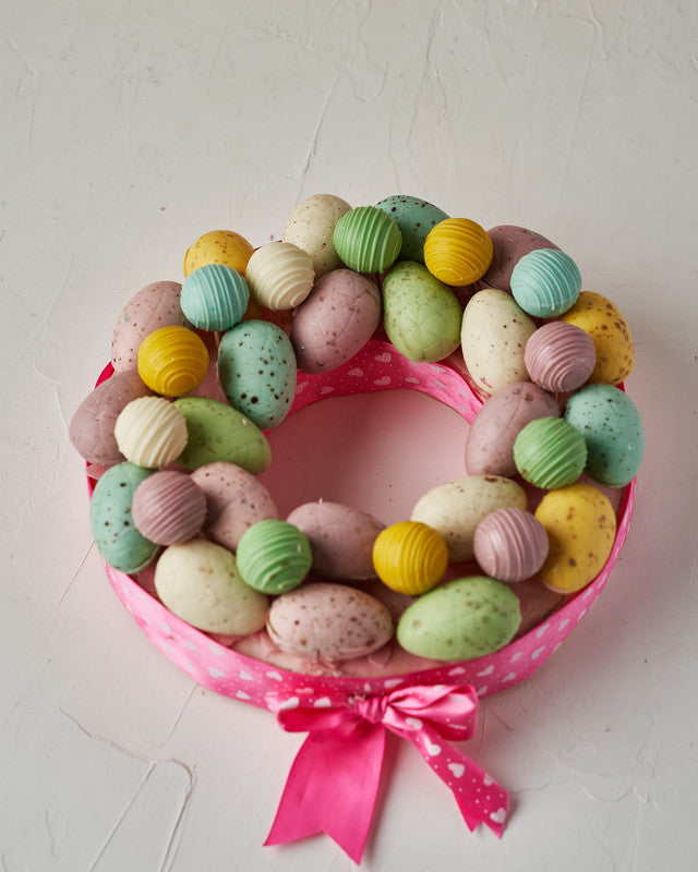 Easter WreathChocolate & ConfectioneryYour Gift Contains: • 12 pieces Belgian chocolate truffles • Flavors: Kinder, Roche, Pistachio and Lotus • 22 pieces assorted color chocolate Easter Eggs • Wreath Size: 23x23x4cm Handling and Storage • Keep away from