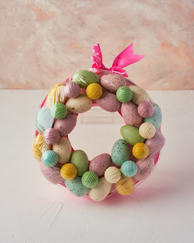 Easter WreathChocolate & ConfectioneryYour Gift Contains: • 12 pieces Belgian chocolate truffles • Flavors: Kinder, Roche, Pistachio and Lotus • 22 pieces assorted color chocolate Easter Eggs • Wreath Size: 23x23x4cm Handling and Storage • Keep away from