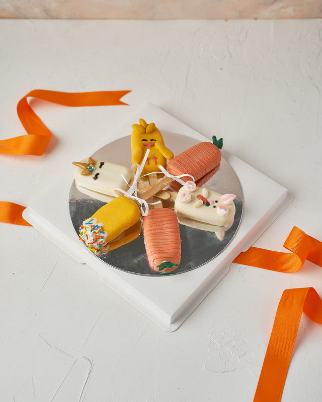 Easter Theme CakesiclesChocolate & ConfectioneryYour Gift Contains: • 3 Red Velvet and 3 Vanilla Cakesicles • Designed as carrots, bunny, unicorn, and chick • Box Size: 23x23x14cm Handling and Storage • Keep away from direct heat and sunlight • Best store