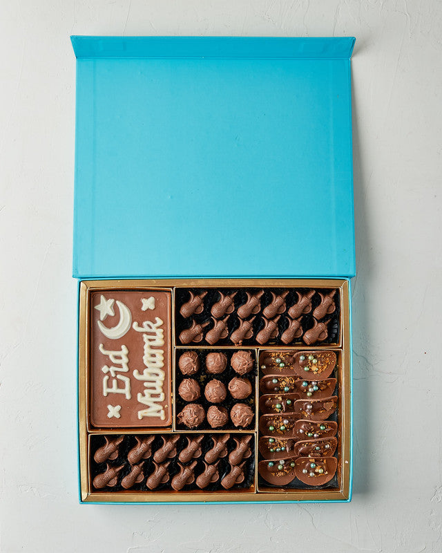 Assorted EID Gift Box by NJDChocolate & ConfectioneryYour Gift Contains: • EID Mubarak Chocolate bar: 25ogms • 24 assorted milk chocolates • Flavours: Pistachio, Peanut Butter, Hazelnut and Dates • 9 milk chocolate truffles • 12 Milk chocolate Tacos • Box