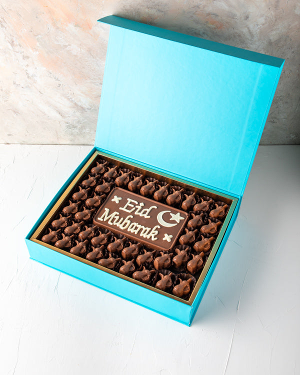 Eid Greetings 41pcs by NJDSweetsYOUR GIFT CONTAINS 41pcs assorted milk chocolates filled with hazelnut, dates and Peanut butter, lotus and pistachio praline flavor 50gms Milk chocolate slab with EID Mubarak Message Box/Tray Size: LxBxH: 31x 25.5x6cm HANDL