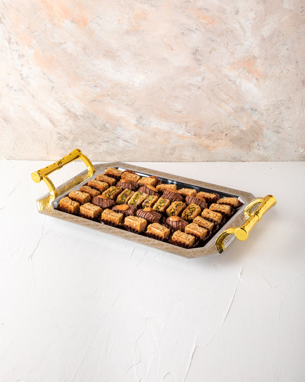 Baklawa and Tray Arrangement by NJDSweetsYour Gift Contains: Milk Chocolate Dates with Almond: 8 pieces Almond Baklawa: 21 pieces Pistachio Baklawa: 7 pieces Box/Tray Size: LxBxH: 35.5x25.6cm HANDLING AND STORAGE Keep away from direct heat and sunlight Ke