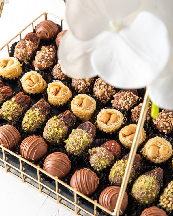 Assorted Ramadan Hamper by NJDSweetsYour Gift Contains: Assorted Belgian milk chocolate truffles: 17pieces Chocolate and Pistachio Dates: 10 pieces Chocolate and Roasted Almonds Dates: 10pieces Baklawa: 8pieces Box/Tray Size: LxBxH: 30x20.5x31.5cm HANDLIN