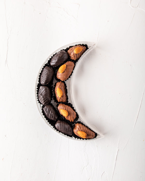 Crescent Dates Collection by NJDChocolate & ConfectioneryYour Gift Contains: Milk chocolate Almond dates - 5pcs Dark Chocolate Covered Dates - 5pcs Box/Tray Size: LxBxH: 7.5x20x5cm HANDLING AND STORAGE Keep away from direct heat and sunlight Keep it refri