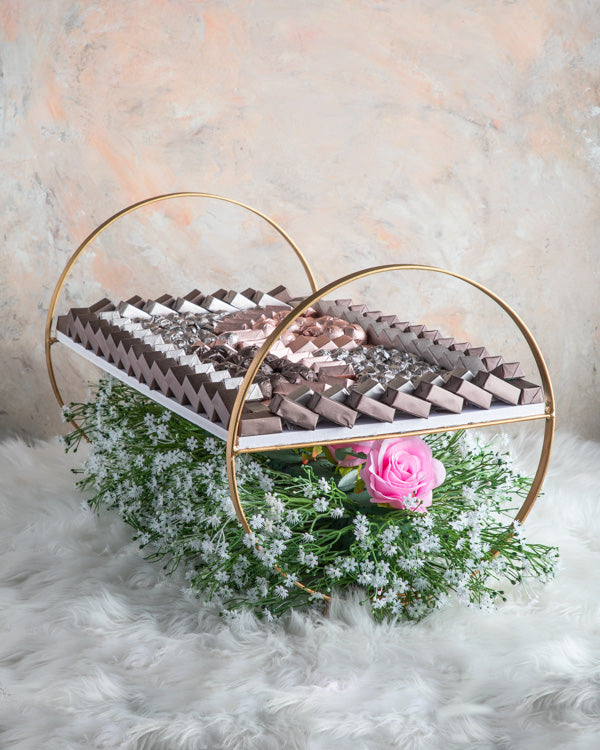 Chocolate Arrangement by NJDChocolate & ConfectioneryApprox. 3kg chocolates on the beautiful tray decorated with faux flowers making a good center piece. 8 fillings: Nutella, Peanut Butter, Salted Caramel, Roasted Nuts, Biscoff, Lotus, Ganache and Praline