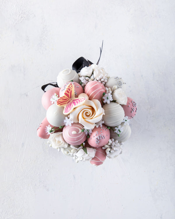 Mini Edible BouquetChocolate & ConfectioneryChocolate covered strawberries 5pcs Chocolate Covered Strawberries 8pcs Belgian chocolate Truffles Edible White Chocolate Rose Edible Butterfly Comes in a beautiful clear pink box Box Dimensions Base: 24.5cmx24.