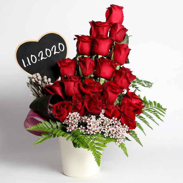 Forbidden Red Roses ArrangementFlowers20 Red Roses White Wax Flower- 1 stem Brunia- 1 stem Seasonal Green Fillers One Black Heart Shaped Board White Vase